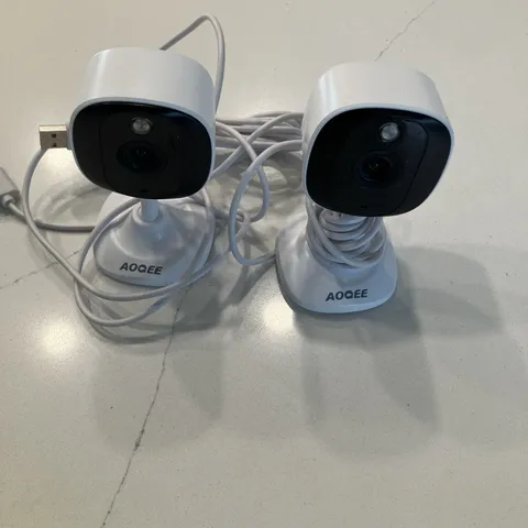 two white AOQEE C1 2K Indoor/Outdoor Security Cameras